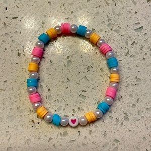 This beautiful bracelet was made by hand. The pattern is orange, pink, and blue.